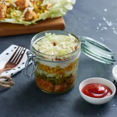 Warstwowa sałatka gyros z kurczakiem i kapustą pekińską w słoiku, z kukurydzą, ogórkiem i sosem.