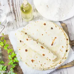 Świeżo usmażone, ciepłe tortilla na patelni, gotowe do nadziewania. Obok mąka, woda i olej.