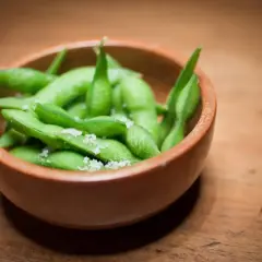 Miseczka pełna zielonej fasolki edamame posypanej solą, gotowa do chrupania.