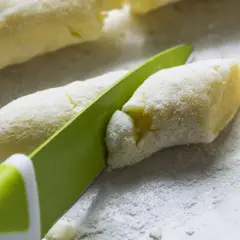 Kopytka z ciasta według przepisu babci, krojenie nożem na mące.