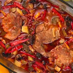 Karkówka po zbójnicku w plastrach, duszona z papryką, pieczarkami i cebulą w aromatycznym sosie. Obok miseczka ryżu.