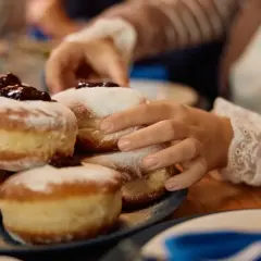 Ręce sięgają po pyszne, pieczone paczki z dżemem i cukrem pudrem, przygotowane na specjalną okazję.