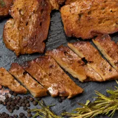 Pokrojony seitan, przypominający mięso, z rozmarynem, pieprzem i solą. To właśnie seitan co to jest – roślinne białko.