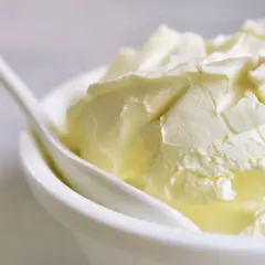 Kremowa masa w białej miseczce z łyżką. Idealna do deserów, gdy szukasz, czym zastąpić mascarpone.