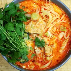 Miseczka zupy curry z makaronem, mięsem i świeżą kolendrą.