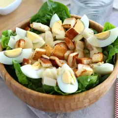 Pyszna sałatka z chrupiącymi grzankami, jajkiem i parmezanem, polana kremowym sosem cezar.