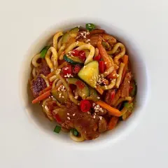 Pyszny, prosty obiad: makaron udon z kurczakiem, cukinią, marchewką i papryczką chili, posypany sezamem.