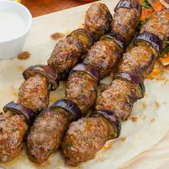 Kofta kebab z bakłażanem na chlebku pita, podany z sosem i sałatką. Pyszne danie, które zachwyci każdego smakosza.