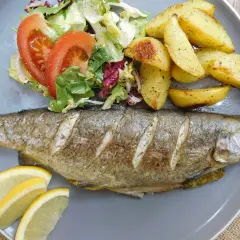 Chrupiący pstrąg z piekarnika, podany z pieczonymi ziemniakami i świeżą sałatką. Idealny obiad!