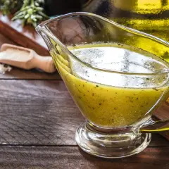 Sos winegret w sosjerce, obok oliwy i przypraw. Idealny przepis na to, jak zrobić sos winegret.