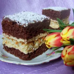 Pyszne ciasto cappuccino na biszkopcie, przełożone kremem i wiórkami kokosowymi, ozdobione wiórkami i tulipanami.