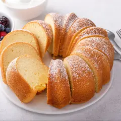 Puszysta babka wielkanocna, posypana cukrem pudrem, z miseczką owoców leśnych obok. Idealna na święta, gdy szukasz prostego przepisu.
