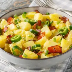 Pyszna niemiecka sałatka ziemniaczana z boczkiem, posypana szczypiorkiem i papryczką jalapeño.