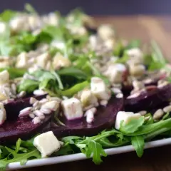 Carpaccio z buraka z serem feta i słonecznikiem, podane na rukoli. Kolorowa i zdrowa przekąska.