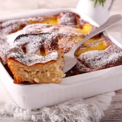 Szybkie ciasto z brzoskwiniami z puszki, posypane cukrem pudrem, wygląda apetycznie. Idealne na deser!