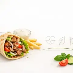 Czy kebab jest zdrowy? Sycący kebab z mięsem, warzywami i frytkami, obok sosu i świeżych dodatków. Ikony serca, liścia i sztućców sugerują zdrowy wybór.