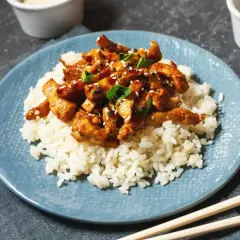 Pyszny kurczak po japońsku w sosie teriyaki, podany na białym ryżu, posypany sezamem i szczypiorkiem.
