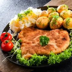 Idealny schabowy na obiad: złocisty kotlet, ziemniaczki, surówka i pomidorki. Prosty przepis, jak zrobić schabowe, by zachwycić rodzinę.