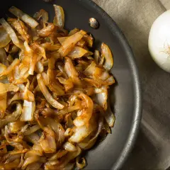 Złocista, karmelizowana cebula w patelni, obok surowa cebula. Idealna do burgerów i zapiekanek.