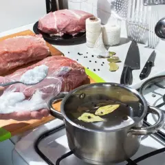Przygotowanie solanki do ryb. Na desce leżą surowe mięsa, obok garnek z wodą i przyprawami.