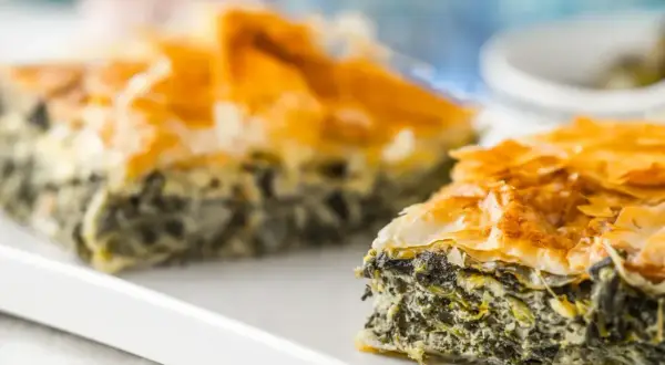 Chrupiąca spanakopita z warstw ciasta filo i zielonym nadzieniem ze szpinaku i sera.