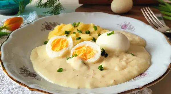Jajka w sosie chrzanowym z ziemniakami, udekorowane szczypiorkiem. Pyszne danie, które rozpływa się w ustach.
