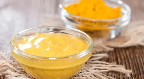 Dwie miseczki z żółtymi przyprawami. Jedna zawiera gęstą pastę, druga proszek. Idealne, gdy zastanawiasz się, czym zastąpić pastę curry.