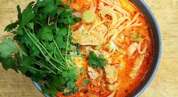Miseczka zupy curry z makaronem, mięsem i świeżą kolendrą.