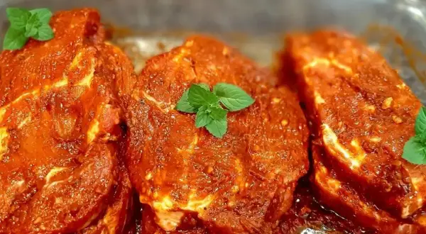 Karkówka w aromatycznej marynacie do karkówki na grilla, ozdobiona listkami mięty. Gotowa na pyszne grillowanie!