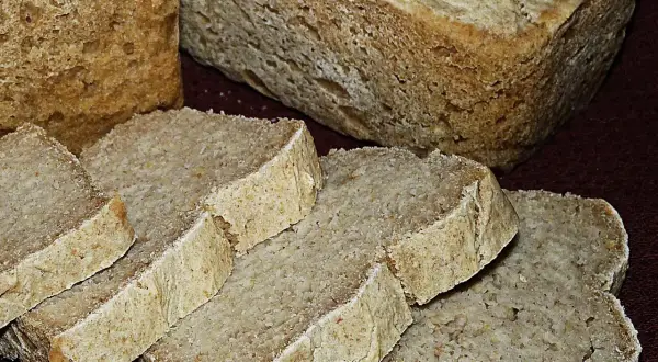 Pokrojony na kromki chleb bez glutenu, z widoczną strukturą miękiszu i chrupiącą skórką. Idealny dla osób na diecie bezglutenowej.