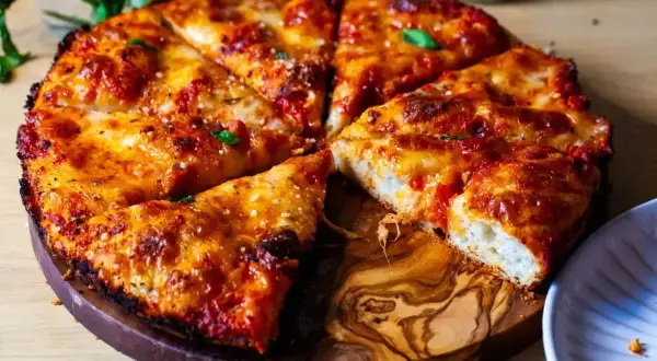 Pyszna pizza rzymska z chrupiącym ciastem, ciągnącym serem i aromatycznym sosem pomidorowym, podana na drewnianej desce.