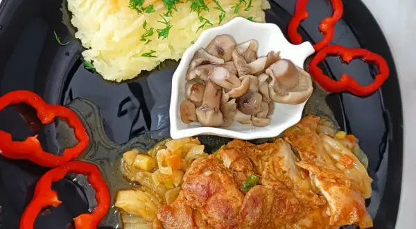 Mięso z udka kurczaka bez kości w sosie, podane z puree ziemniaczanym, marynowanymi grzybami i papryką. Idealne na obiad.