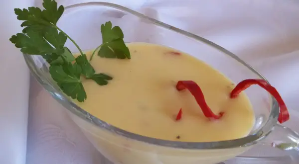 Kremowy sos cytrynowy do ryby, ozdobiony natką pietruszki i papryczką chili.