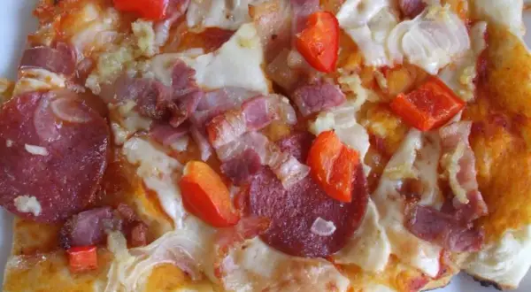 Pikantna pizza diavola z salami, boczkiem i papryką, gorąca i apetyczna.