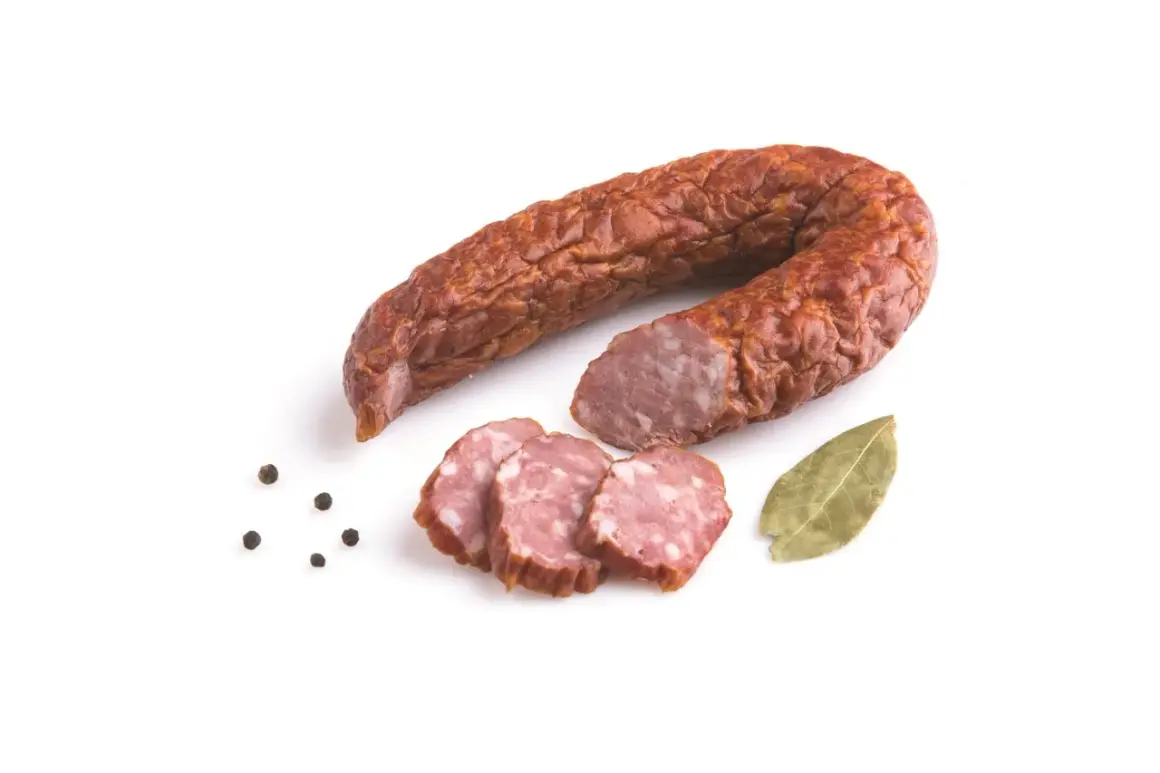 Krągła, wędzona kiełbasa jałowcowa, pokrojona w plastry, z ziarnami pieprzu i liściem laurowym.