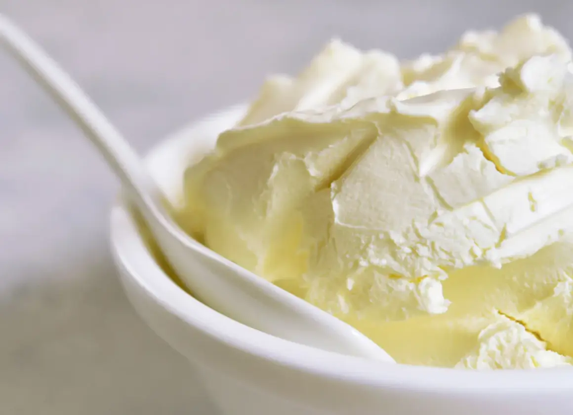 Kremowa masa w białej miseczce z łyżką. Idealna do deserów, gdy szukasz, czym zastąpić mascarpone.