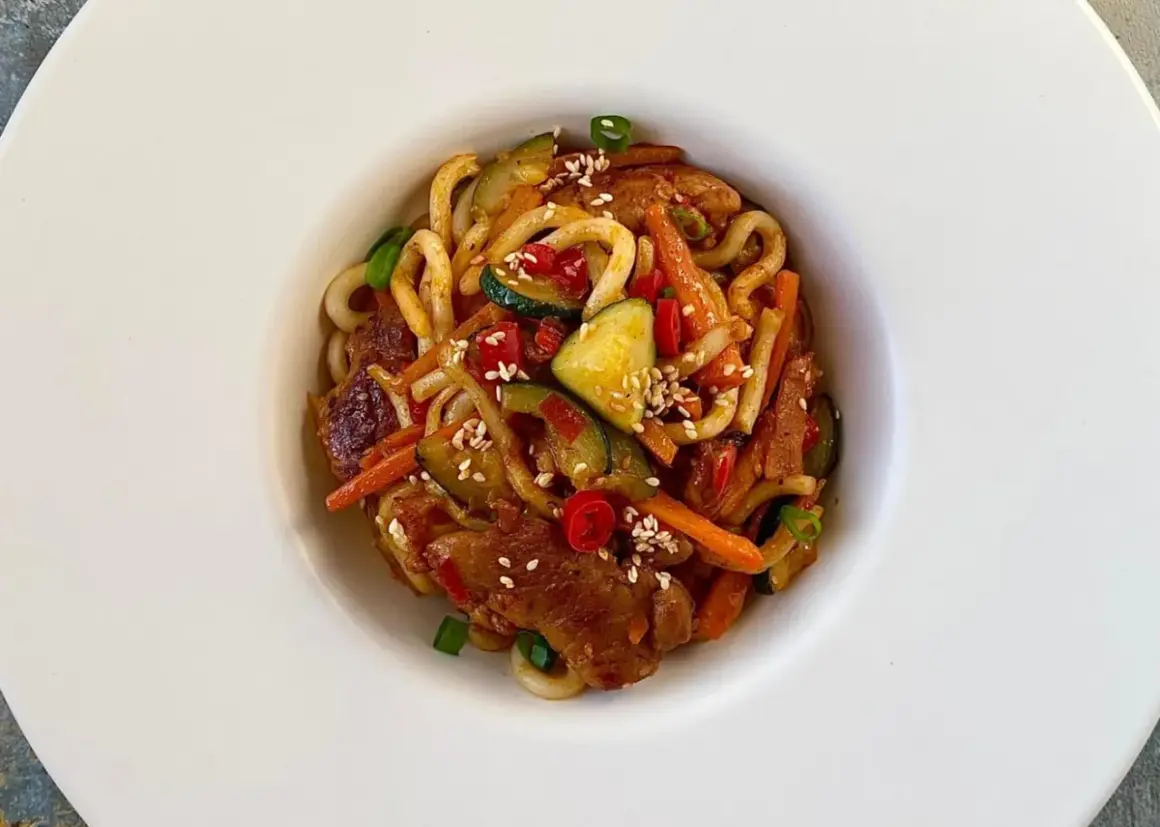 Pyszny, prosty obiad: makaron udon z kurczakiem, cukinią, marchewką i papryczką chili, posypany sezamem.