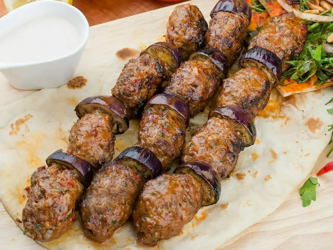 Kofta kebab z bakłażanem na chlebku pita, podany z sosem i sałatką. Pyszne danie, które zachwyci każdego smakosza.