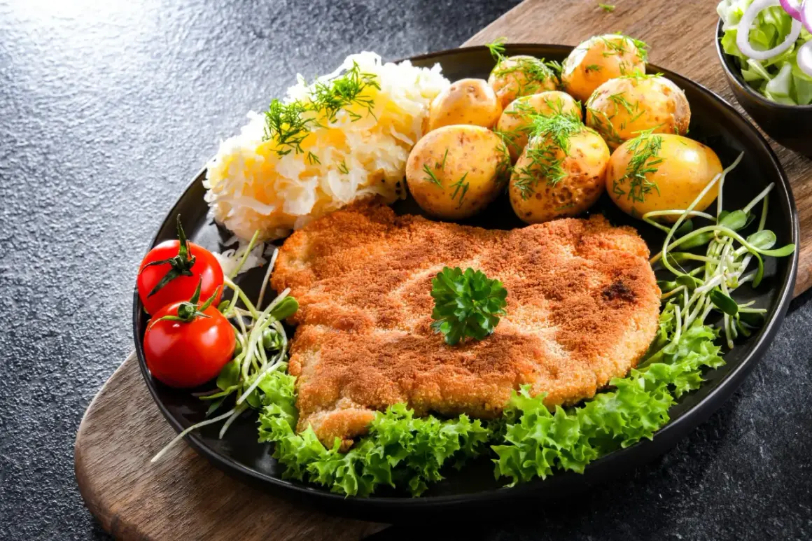 Idealny schabowy na obiad: złocisty kotlet, ziemniaczki, surówka i pomidorki. Prosty przepis, jak zrobić schabowe, by zachwycić rodzinę.