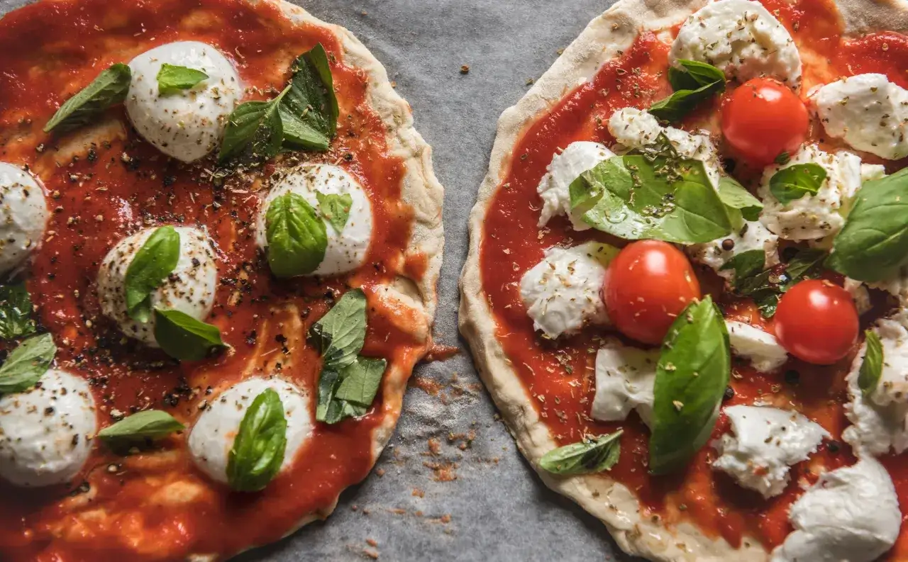 Dwie pizze margherity w przygotowaniu: sos pomidorowy, kulki mozzarelli i świeża bazylia. Idealny ser do pizzy.