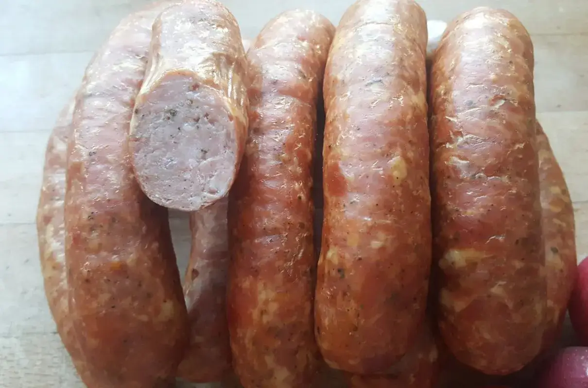 Gotowy przepis na kiełbasę swojską 5 kg. Wędliny wyglądają apetycznie, z widocznymi przyprawami.