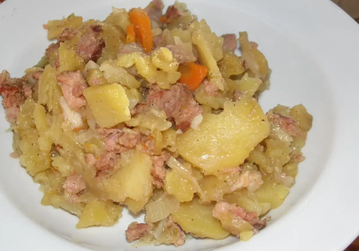 Pyszne, domowe duszonki z ziemniaków, mięsa i marchewki na białym talerzu.
