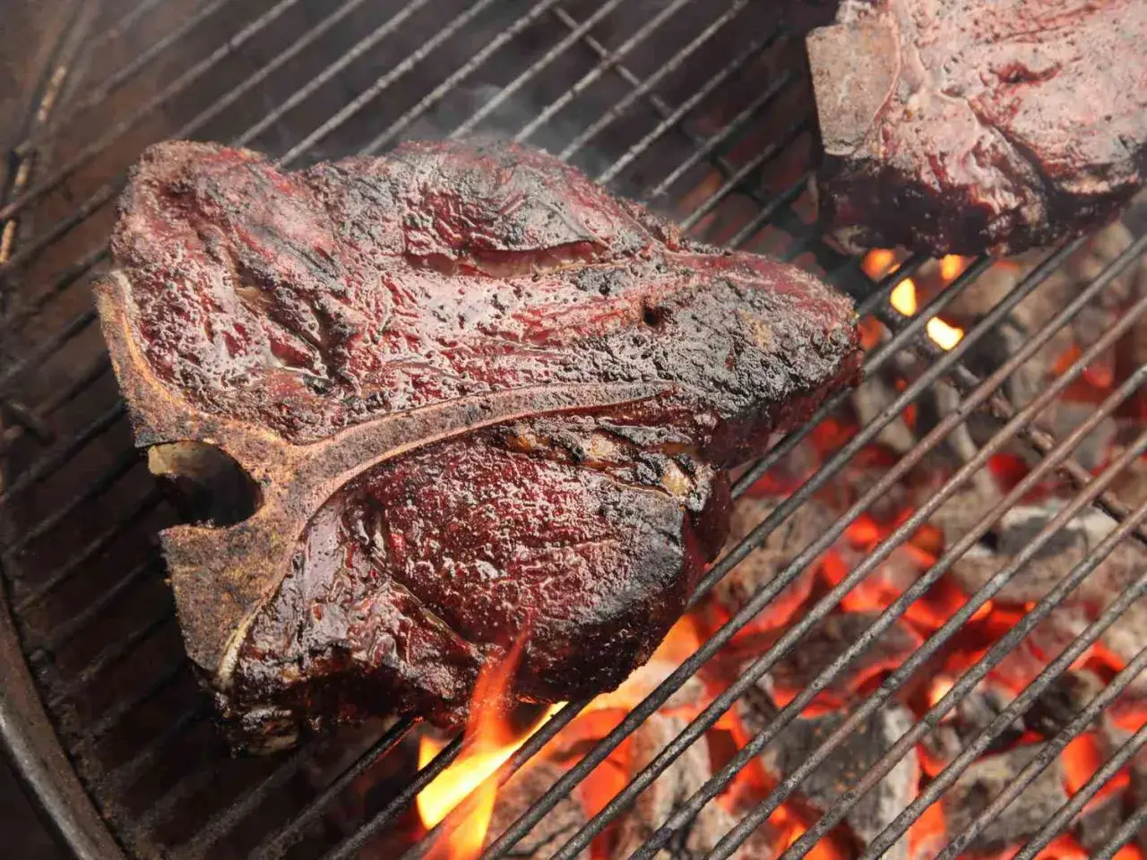 Soczyste steki T-bone grillują się nad żarem, tworząc apetyczny aromat.